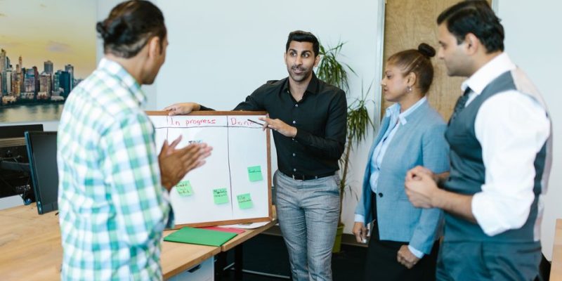 Diverse team discussing project progress with a board in a modern office.