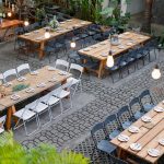 Scenic outdoor venue setup with rustic tables and floral decorations.