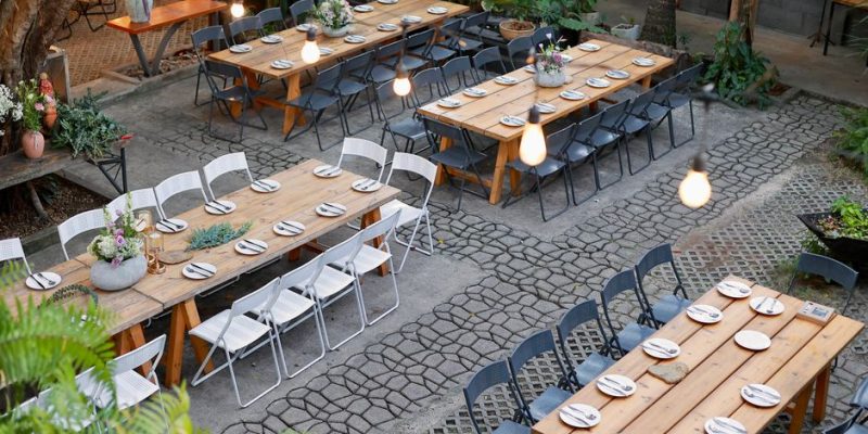 Scenic outdoor venue setup with rustic tables and floral decorations.